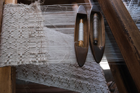 Close-up of an old loom and white threads of yarn and an old wooden shuttle. Hand weaving....
