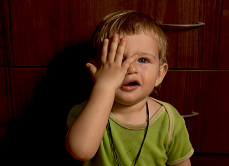 Little playful boy closes eyes a hand jokinglyの写真素材