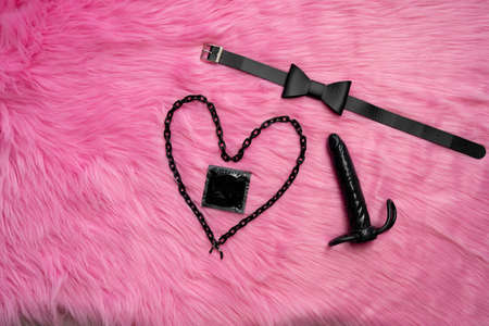 Concept of safe sex and couple games.  Condom next to heart and butterfly tie and dark vibrator. Adult content of sex toysの写真素材