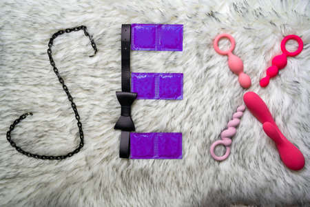 the word sex made of sex toys and condoms on gray fur background, concept of seduction, introduction to couple gameの写真素材