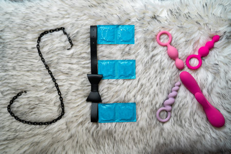 the word sex made of sex toys and condoms on gray fur background, concept of seduction, introduction to couple gameの写真素材