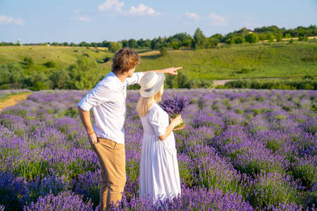 couple in white matching outfit in lavender field, photo session. man is proposing to woman with ring. engagement day. romance and true love in relationship. They are happy huggingの写真素材