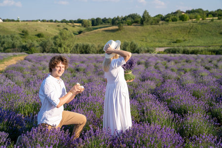 couple in white matching outfit in lavender field, photo session. man is proposing to woman with ring. engagement day. romance and true love in relationship. They are happy huggingの写真素材