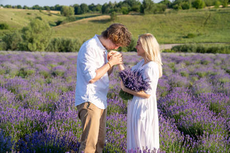 couple in white matching outfit in lavender field, photo session. man is proposing to woman with ring. engagement day. romance and true love in relationship. They are happy huggingの写真素材