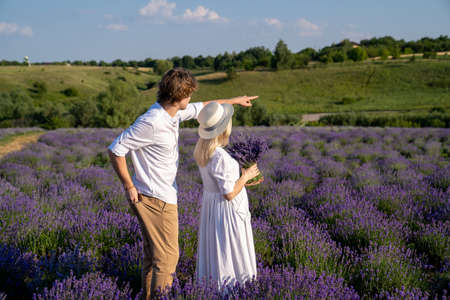 couple in white matching outfit in lavender field, photo session. man is proposing to woman with ring. engagement day. romance and true love in relationship. They are happy huggingの写真素材