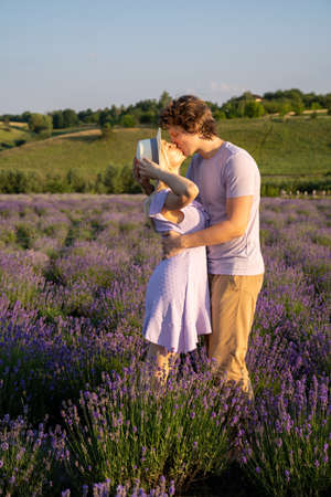 couple in purple matching lilac outfit, hugging, kissing in lavender field. Romantic date concept, perfect relationship. Good picture for cover, calendar, postcard, wallpaperの写真素材