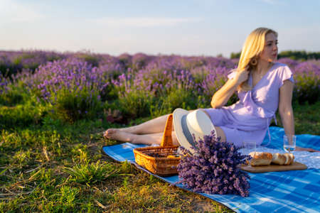beautiful woman in purple lilac outfit has picnic in lavender field, photo session of leisureの写真素材
