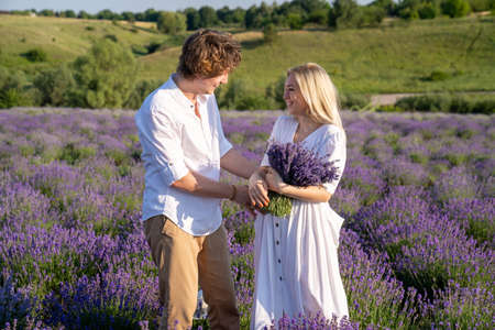 couple in white matching outfit in lavender field, photo session. man is proposing to woman with ring. engagement day. romance and true love in relationship. They are happy huggingの写真素材