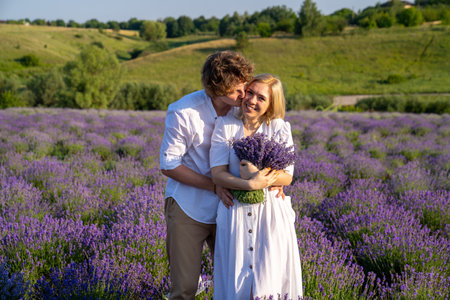 couple in white matching outfit in lavender field, photo session. man is proposing to woman with ring. engagement day. romance and true love in relationship. They are happy huggingの写真素材