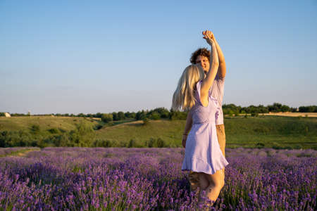 romantic couple in purple matching outfit in love dancing together in lavender fieldの写真素材
