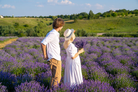 couple in white matching outfit in lavender field, photo session. man is proposing to woman with ring. engagement day. romance and true love in relationship. They are happy huggingの写真素材