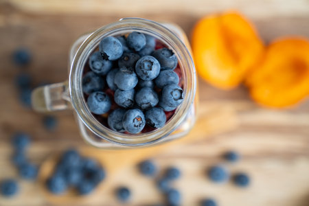 blur background, top view on healthy, organic, gluten free breakfast served in transparent glass cup filled with blueberry and apricot on a wooden plate, near wooden spoon. Healthyの写真素材