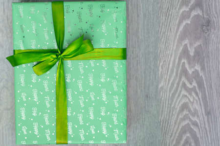 top view of green turquoise color gift box with green ribbon bow on grey wooden background. Concept: holiday, celebration, birthday, New Year, Christmas, Valentines Day, Mothersの写真素材