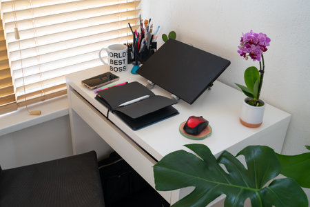 modern workplace: table desk with laptop, stationery, orchid plant, open white textbook with pen. Concept of work, work from home, study, back to school, home officeの写真素材