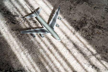 creative effect with sun light beam, airplane aircraft toy on grey background with lines, travelling concept, jet planeの写真素材