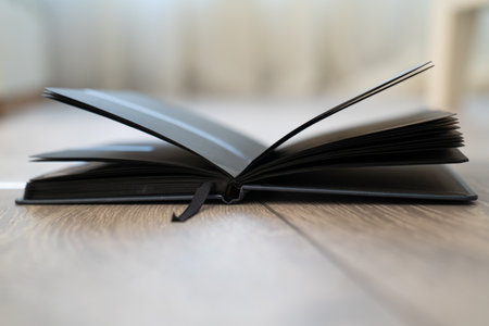 open text book on wooden background, black color of pages, creative effect lines of sun light...