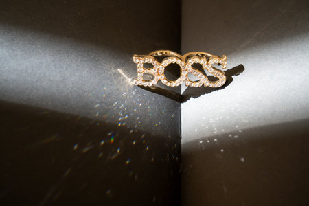 a closeup shot of a beautiful gold ring Boss on a black background, book, shining sparkles, woman lifestyle fashionの写真素材