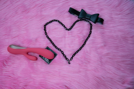 sex toys, adult toy vibrator and condom, concept of safe sex, protection, heart on pink fur background, dark bow tie, couple games in healthy relationship, love on valentines dayの写真素材