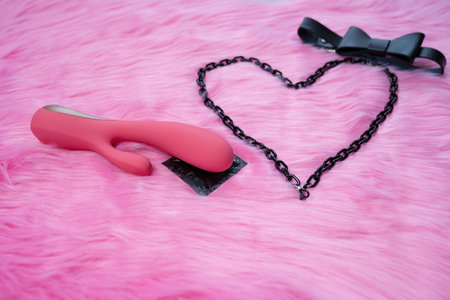sex toys, adult toy vibrator and condom, concept of safe sex, protection, heart on pink fur background, dark bow tie, couple games in healthy relationship, love on valentines dayの写真素材