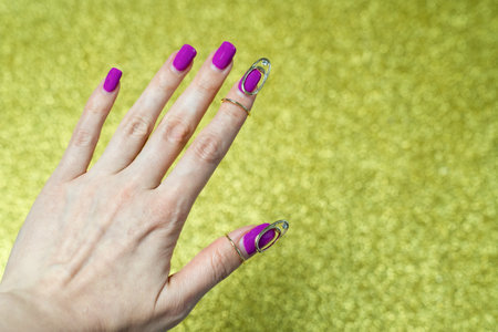beautiful female hand with manicure on gold background, nail decor jewelry, art design, creative accessoriesの写真素材