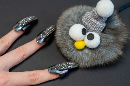 Halloween theme, witch nails, beautiful female hand with stylish manicure and jewellery, nail rings, decoration, magic, spooky, black background, plush toy monster with eyesの写真素材
