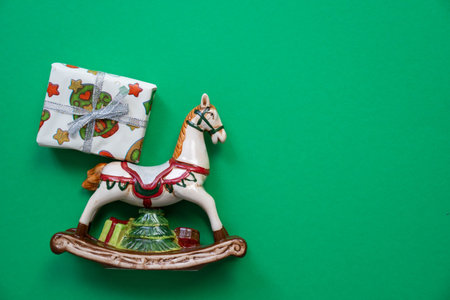 toy horse porcelain figure with wrapped gift box, merry christmas and happy new year decorations on a green background, festive holiday surprise, copy space, gifts delivery serviceの写真素材
