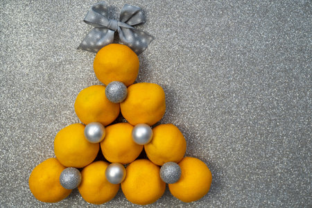 happy holidays, merry christmas, new year atmosphere, christmas tree made of tangerines and decorated with baubles silver balls, bow star on top, celebration time, festive seasonの写真素材
