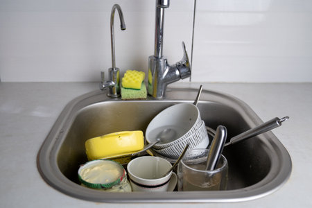 dirty dishes in kitchen sink, pile of utensils need wash, a lot of tableware, lazy housewife concept, perfectionist hellの写真素材