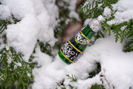 champagne bottle christmas decoration toy on snowy fir tree branch. New year holiday celebration in winter forest. Festive wonderful timeの写真素材