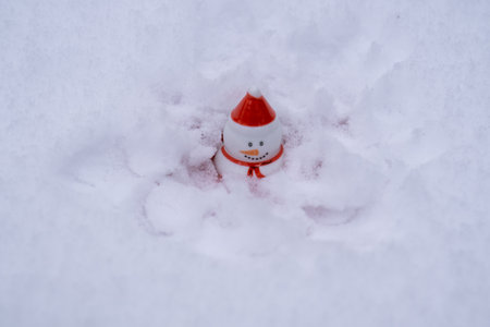 snowman with red hat sitting in snow. Christmas and new year winter holidays concept. White background, extreme cold weatherの写真素材