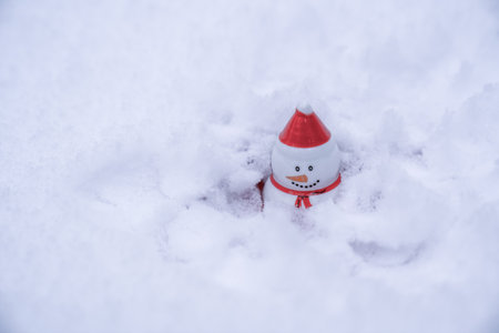 snowman with red hat sitting in snow. Christmas and new year winter holidays concept. White background, extreme cold weatherの写真素材