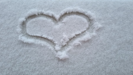 heart shape writing on clear white snow on street, winter romance, first snowの写真素材