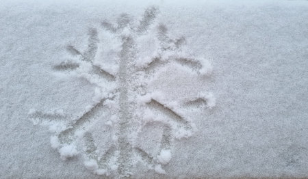 snowflake shape writing on clear white snow on street, winter begins, first snowの写真素材