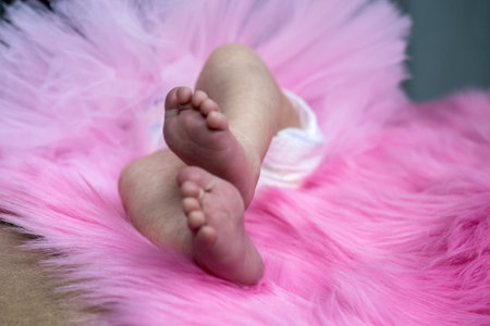cute newborn baby tiny soft feet on pink blanket, infant baby girl in diaper and fatin skirtの写真素材