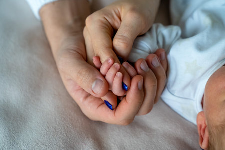 father and mother holding newborn baby's hand, close up family hold hands together, parent's love, tiny little fingers, happiness and careの写真素材