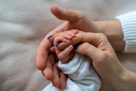 father and mother holding newborn baby's hand, close up family hold hands together, parent's love,...