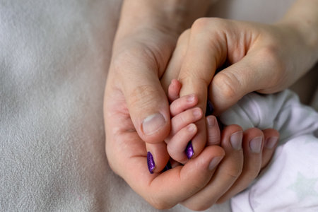 father and mother holding newborn baby's hand, close up family hold hands together, parent's love, tiny little fingers, happiness and careの写真素材