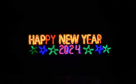 Happy New Year 2024 illuminated sign on black background. Happy winter holidays made of lights and garland. Street advertisement. Outdoor signboard.の写真素材