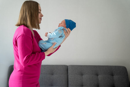 young loving mother holds newborn baby son in hands. Taking care of infant, parenting, raising...