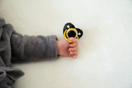 baby hand holds pacifier. Soothe infant, newborn.