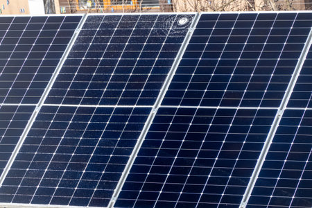 Cracked solar panel with visible impact damage on photovoltaic module installed outdoors. Broken glass surface on renewable energy system highlighting maintenance issues, energy loの写真素材