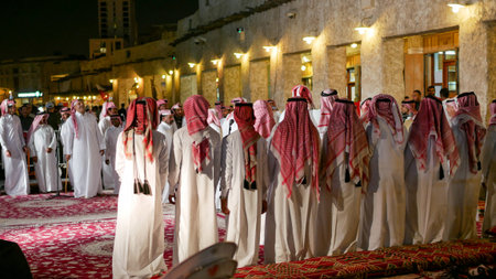 Doha, Qatar - March 19 2025: Qatari men in traditional clothing performing cultural dance at night...