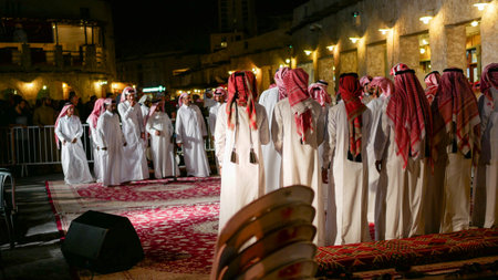 Doha, Qatar - March 19 2025: Qatari men in traditional clothing performing cultural dance at night event in Souq Waqif.のeditorial素材