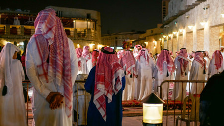 Doha, Qatar - March 19 2026: Qatari men in traditional clothing gathering at night cultural event in Souq Waqif.のeditorial素材