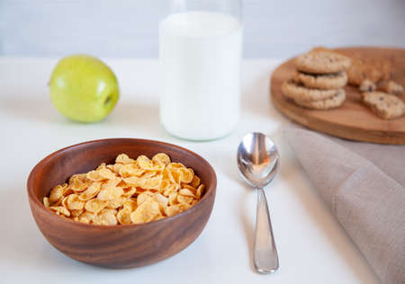 Corn flakes in a wooden plate and bottle of milk on the table. Healthy breakfast.