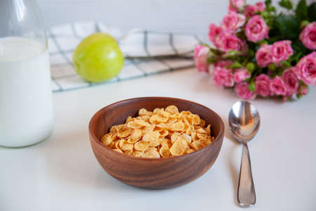 Corn flakes in a wooden plate and bottle of milk on the table. Healthy breakfast.の写真素材