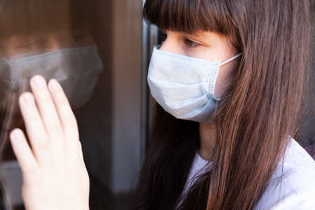 Girl in isolation. Protective medical mask on the face against Coronavirus. Stop COVID-19の写真素材