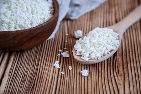 Wooden bowl with cottage cheese and spoon on the wooden table.Healthy product.の写真素材