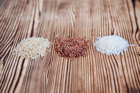 Different types of rice on a wooden background. White, brown and red.の写真素材