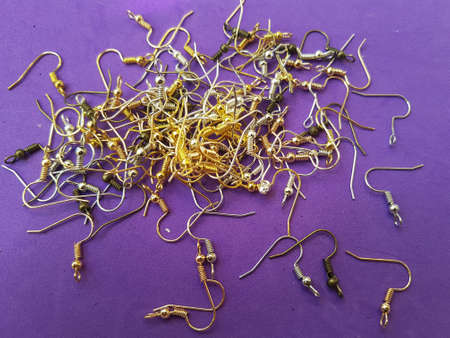 A lot of laid out golden schwenz hooks on a purple background Earring accessory Materials for creating jewelryの写真素材